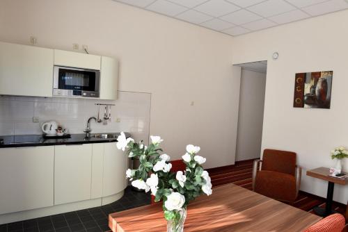 a kitchen with a table with a vase of flowers on it at SuyderSee Hotel in Enkhuizen