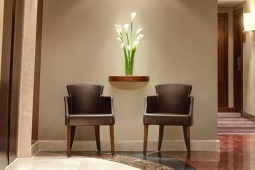 two chairs and a vase of flowers on a wall at Elaf Kinda Hotel in Makkah