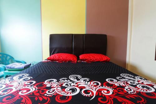 a black and red bed with two red pillows on it at Hotel Grand Family in Sungairampah
