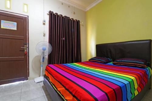 a bedroom with a bed with a colorful striped blanket at Hotel Grand Family in Sungairampah