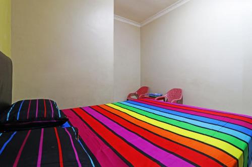 a bed with a rainbow colored blanket on it at Hotel Grand Family in Sungairampah
