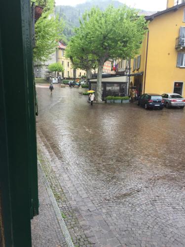 a wet street with cars parked in the rain at Petit Bijou in Varenna