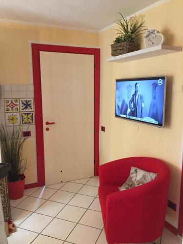 a living room with a red chair and a flat screen tv at Petit Bijou in Varenna