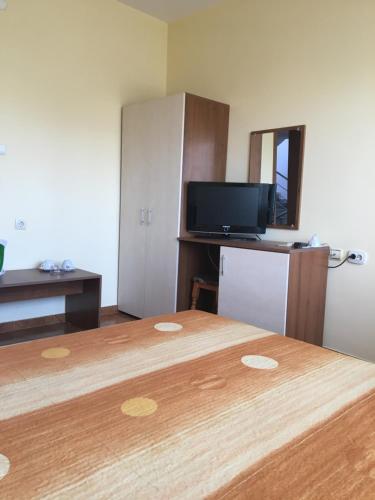 a room with a bed with a television and a bedskirtspectspectspectspects at Tonus Guest House in Obzor
