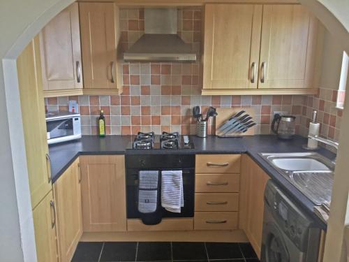 a kitchen with wooden cabinets and a stove top oven at The Loft Guest Apartment in Portstewart