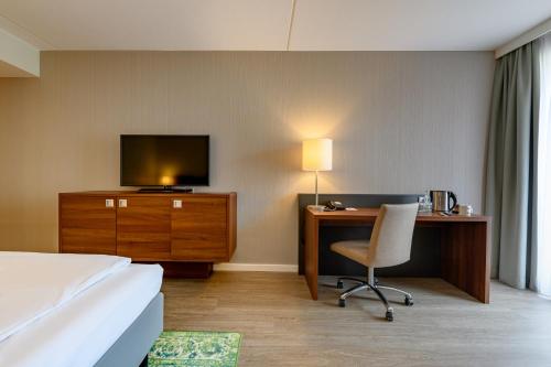 a hotel room with a bed and a desk and a television at Mercure Stuttgart Sindelfingen an der Messe in Sindelfingen