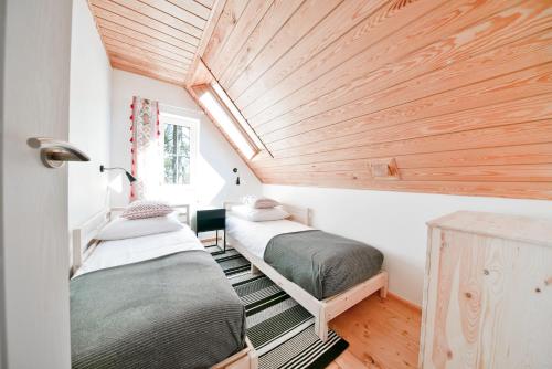 two beds in a room with a wooden ceiling at Górski Domek koło Karpacza- Apartamentuj in Karpacz