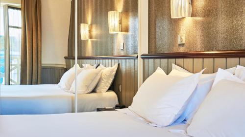 two beds in a hotel room with white pillows at Hôtel Le Beaufort in Saint Malo