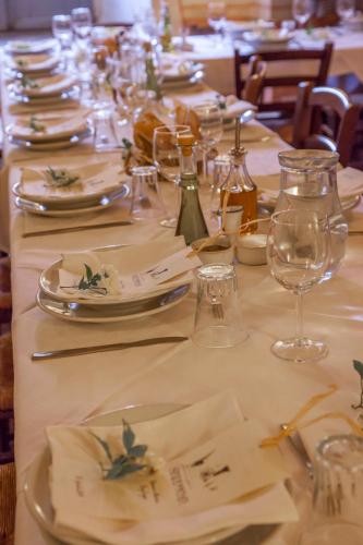 una mesa larga con platos blancos y copas de vino en Tenuta di Spannocchia, en Rosia