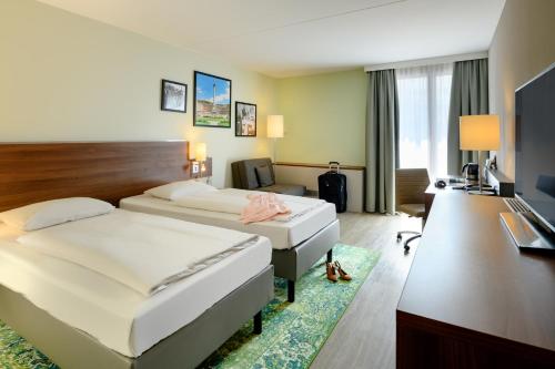 a hotel room with two beds and a desk at Mercure Stuttgart Sindelfingen an der Messe in Sindelfingen