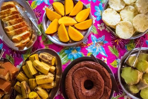 einen Tisch mit verschiedenen Arten von Gebäck und Kuchen in der Unterkunft O Pharol Hostel e Pousada in Itacaré