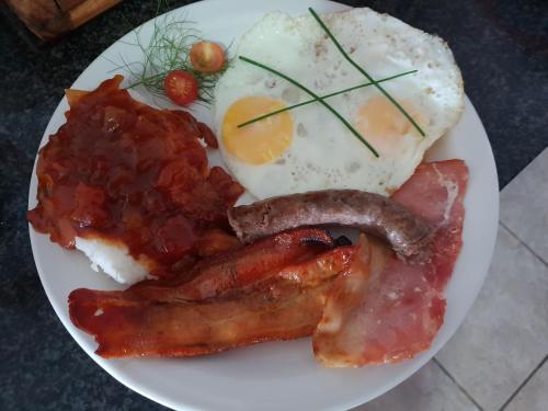 a plate of breakfast food with bacon eggs and sausage at Dilisca Guesthouse in Durbanville