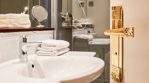 a bathroom with a sink and a mirror and towels at Hôtel Le Beaufort in Saint Malo