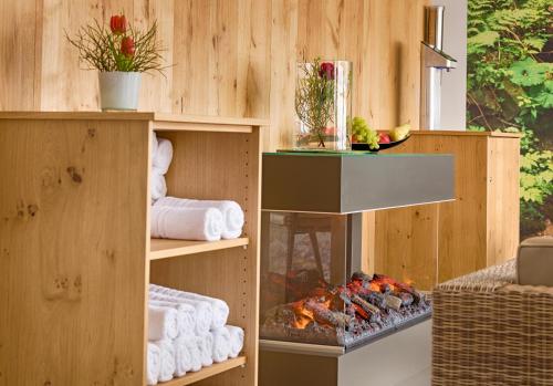 a fireplace in a room with towels and a grill at BRUGGER'S Hotelpark am See in Titisee-Neustadt