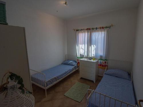 a small room with two beds and a window at Villa Fiore con Piscina e Vista Mare in Palau