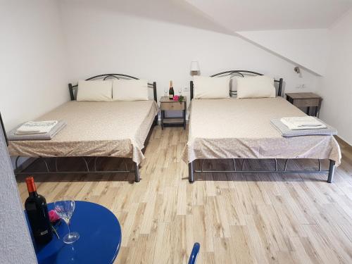 two beds in a room with a blue table at Villa Giannis Apartments in Nea Vrasna