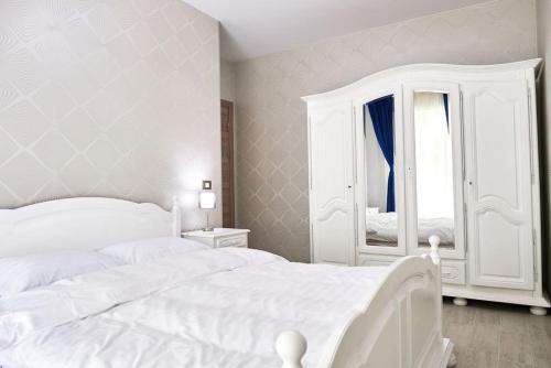 ein weißes Schlafzimmer mit einem weißen Bett und einem Spiegel in der Unterkunft Blue Apartment in Spa n Pool Beach resort in Mamaia Nord – Năvodari