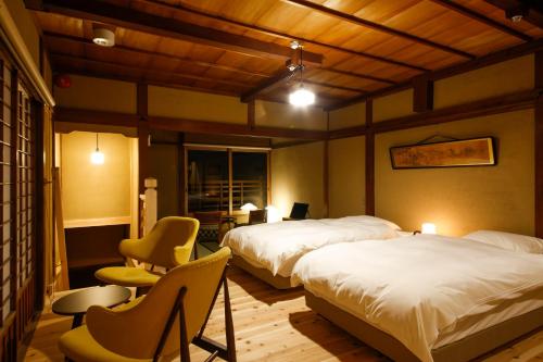 a room with two beds and two chairs in it at Kariya Ryokan Q in Ako