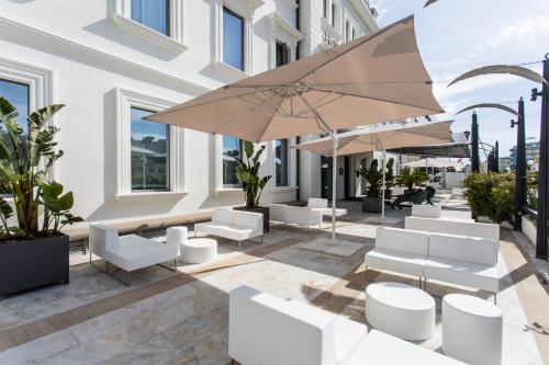a patio with white chairs and umbrellas at Kursaal Hotel in Cattolica