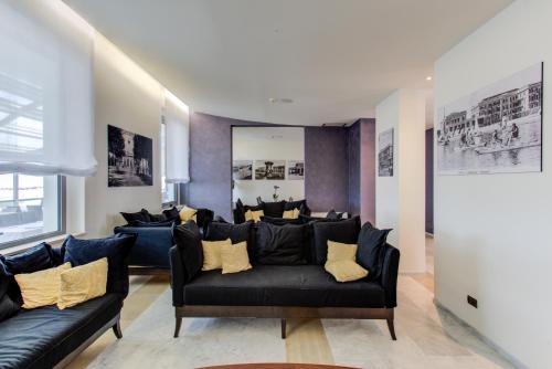 a living room with black leather couches and yellow pillows at Kursaal Hotel in Cattolica