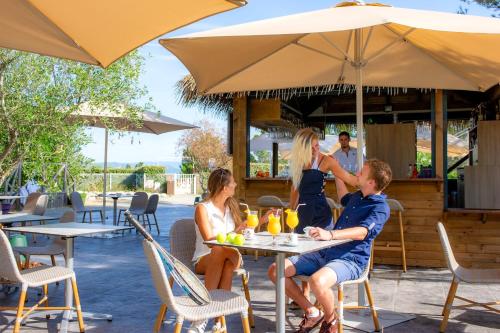 a group of people sitting at a table under an umbrella at VTF Le Castelet in Saint-Aygulf