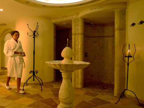 a woman standing next to a sink in a bathroom at Hotel Alle Alpi in Moena