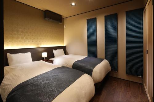two beds in a hotel room with windows at Kanade Kyoto-Hachijoguchi in Kyoto