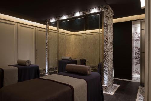 a room with two beds and a wall with a mirror at The Lanesborough, Oetker Hotels in London