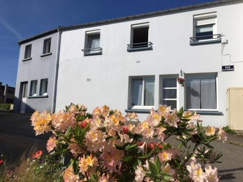 a white house with flowers in front of it at Bel appartement dans maison au bourg in Loc-Maria-Plouzané