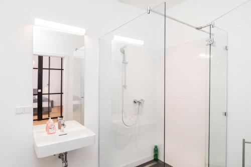 a white bathroom with a shower and a sink at Mint@Naschmarkt Premium Apartments in Vienna