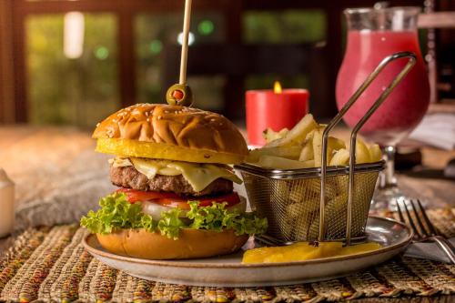 a hamburger and french fries on a table with a candle at Hotel Finca Buenos Aires Barichara in Barichara