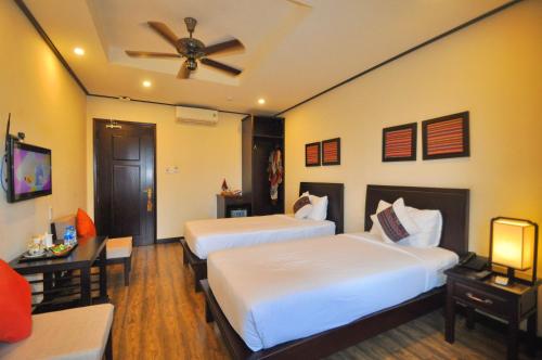 a hotel room with two beds and a ceiling fan at The Quin Riverside Villa in Hoi An