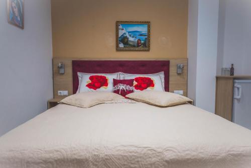 a large white bed with red flowers on it at Hotel Dimitra Sun in Archangelos