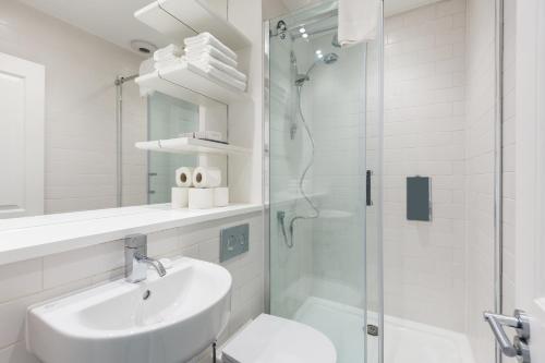 a white bathroom with a sink and a shower at Urban Chic - Covent Garden in London