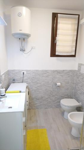 a bathroom with a toilet and a sink and a mirror at Apartment Mistral in Badesi