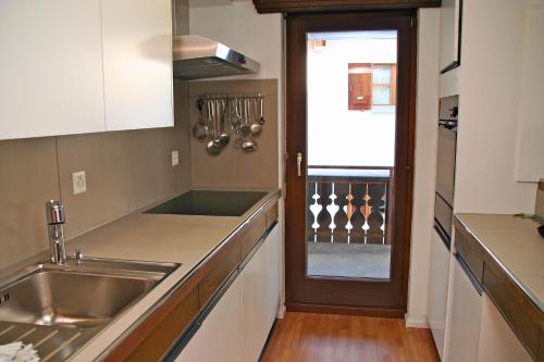 a kitchen with a sink and a door with a window at Monami Apartments Klosters, Apt. Casa Selva Nr 10 in Klosters