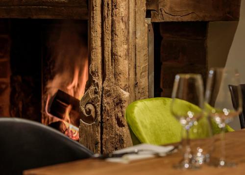 a table with a fireplace and a glass of wine at Hôtel La Garenne in Saverne