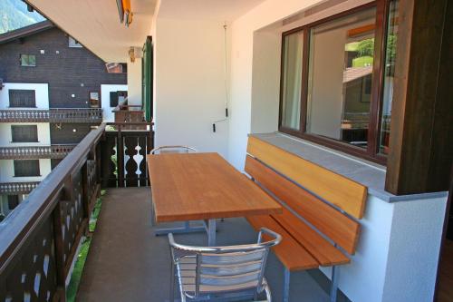 a balcony with a wooden table and a window at Monami Apartments Klosters, Apt. Casa Selva Nr 10 in Klosters