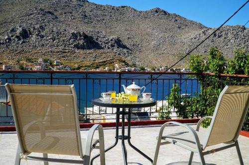two chairs and a table with a tea set on a balcony at Agnanti house in Symi