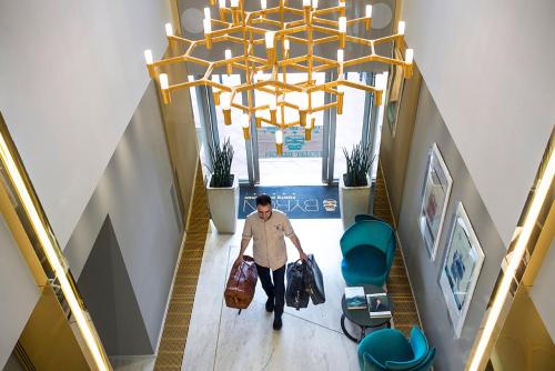 a man walking down a hallway with a large chandelier at Hotel Byron in Forte dei Marmi