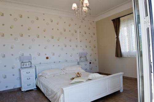 a white bedroom with a white bed and a chandelier at Le Torri Villas by Nidri holiday villas in Nydri