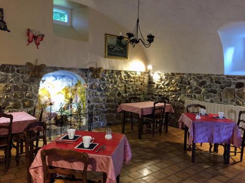 a restaurant with tables and chairs and a stone wall at Le Manoir du Raveyron in Vallon-Pont-dʼArc