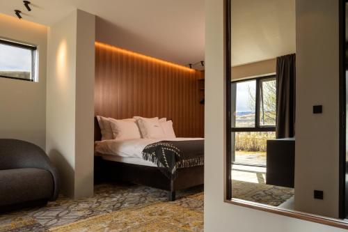 a bedroom with a bed with a mirror and a window at ION Adventure Hotel, Nesjavellir, a Member of Design Hotels in Nesjavellir