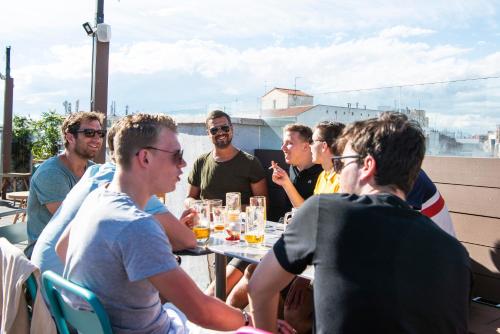 a group of men sitting around a table on a rooftop at Safestay Madrid Central in Madrid