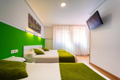 two beds in a room with a green wall at Hotel Centro Vitoria AutoCheckIn in Vitoria-Gasteiz