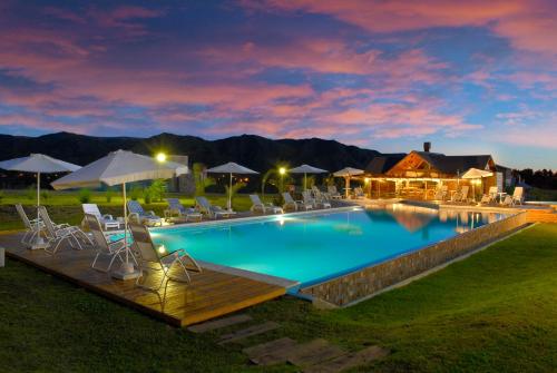 una gran piscina con sillas y sombrillas en Chamonix Posada & Spa Habitaciones dentro de la posada o Loft con hidromasaje y apartamentos a 300 mts de la posada en Villa General Belgrano