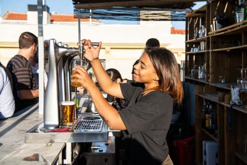a woman is making a drink at a bar at Safestay Madrid Central in Madrid