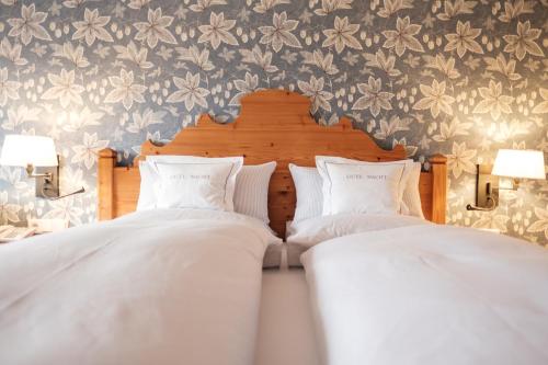 two beds in a bedroom with flowers on the wall at Landhaus am Stein in Bad Wiessee