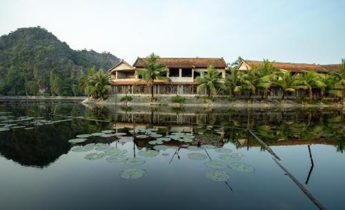 a house sitting on top of a lake with lilies at Ruby Homestay in Ninh Binh