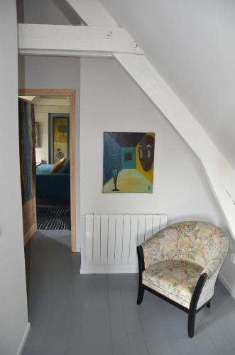 una sala de estar con una silla y una pintura en Ô Grenier de l'artiste, en Bazenville